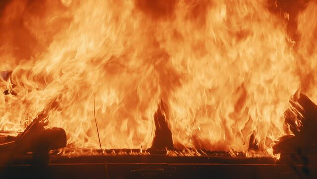 Footage of burning car outdoors during street riots at night time. Road accident at night. Close-up view of abandoned automobile on fire