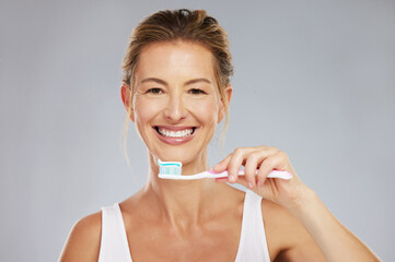 Teeth, dental and oral hygiene with a woman brushing using a toothbrush and toothpaste in a studio...