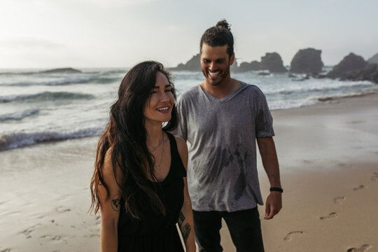 happy and tattooed woman smiling near cheerful boyfriend on beach.