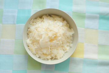 fresh coconut flakes in a bowl on a table cloth 