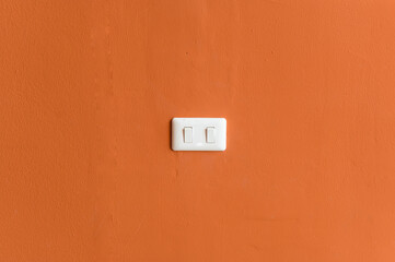 Double wall light switch is an on-off light switch. Power supply to save electricity in Thailand, the switch is white and the background is orange.