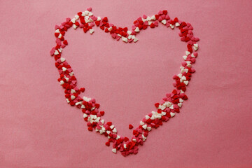 A heart lined with candy hearts on a rochs background. Pink, white, red hearts. Love. Simovl loves. Valentine is Day. Lots of little hearts. Copy space for text.