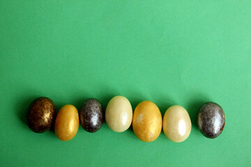 Chocolate eggs on a green background for Easter. The eggs are multicolored. Happy Easter. Chocolate. Sweets for children and adults. Candy. Dessert. Copy space. Top view. Flat lay