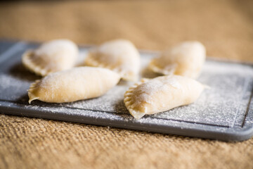 Raw dumplings . Dumplings cooking on a kitchen cutting board.