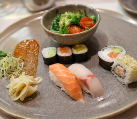 Ein Teller mit Salat und Sushi Rollen, frischer roher Fisch.