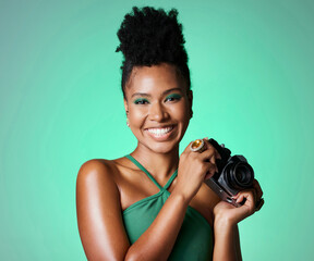 Photography, camera and portrait of a happy black woman standing in a studio with a green background. Happy, smile and professional young african creative female photographer from south africa.