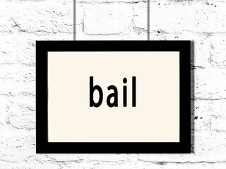 Black frame hanging on white brick wall with inscription bail