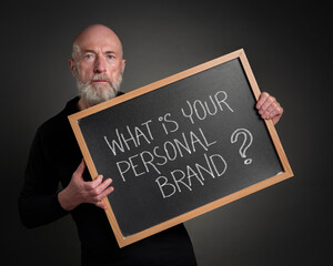 What is your personal brand? A senior man, teacher, mentor or presenter, with a blackboard sign. Branding and marketing concept.