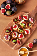 Toasts with figs, ricotta and fig marmalade sprinkled with honey on wooden board