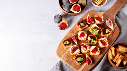 Toasts with figs, ricotta and fig marmalade sprinkled with honey on wooden board