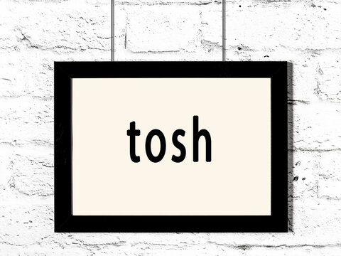 Black frame hanging on white brick wall with inscription tosh