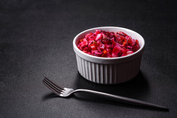 Traditional ukrainian beetroot salad vinaigrette on a white plate on a black concrete or slate background