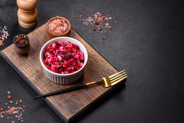 Traditional ukrainian beetroot salad vinaigrette on a white plate on a black concrete or slate...