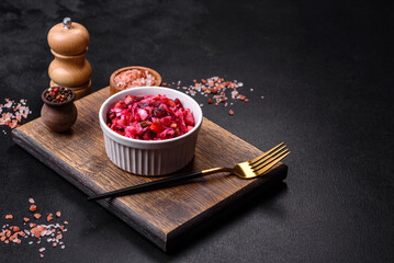 Traditional ukrainian beetroot salad vinaigrette on a white plate on a black concrete or slate background