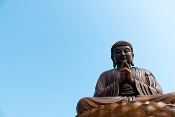 Fototapeta premium Wooden Buddha statue under blue sky
