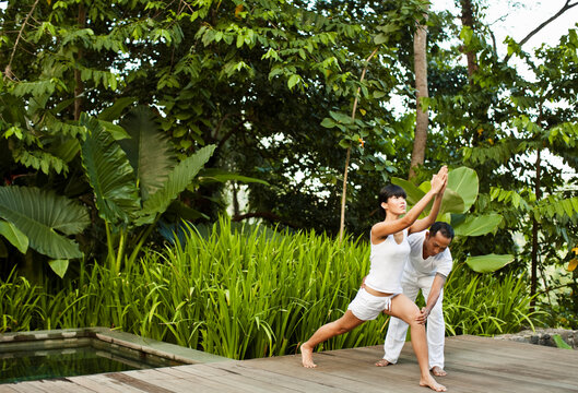A woman practices yoga during a private teaching session at a hotel pool villa. Ubud, Bali, Indonesia