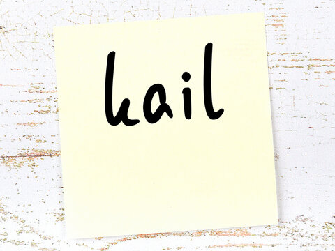 Yellow sticky note on wooden wall with handwritten word kail