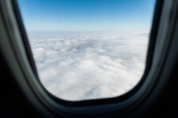 Plane window view with fluffy clouds