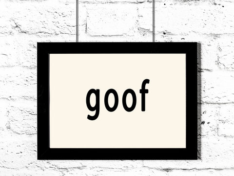 Black frame hanging on white brick wall with inscription goof