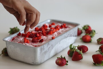 Homemade strawberry ice cream taken out from freezer in a loaf tin served with strawberry slices on...