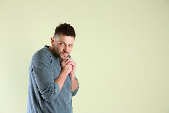 Greedy man rubbing hands on light background, space for text