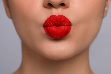 Closeup view of beautiful woman puckering lips for kiss.on grey background - obrazy, fototapety, plakaty