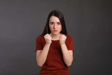 Portrait of emotional young woman on dark grey background. Personality concept