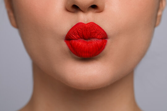 Closeup view of beautiful woman puckering lips for kiss.on grey background