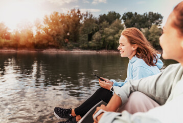 Two young happy caucasian women girlfriends are relaxing on a boat on the river at sunset