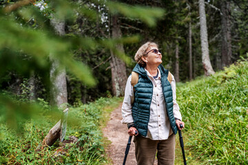 Active happy mature senior woman walking in beautiful autumn forest