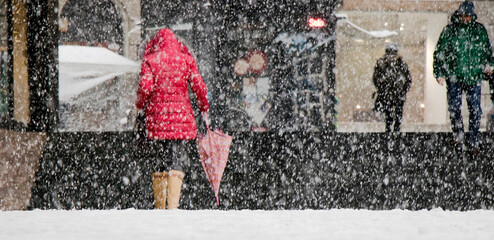 Pedestrians walking city street on a snowy day - 535880696