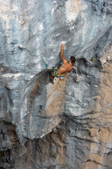 Extreme sport, strong man, rock climber climbs a difficult route.