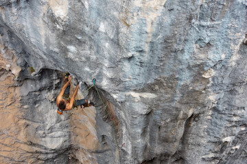 Extreme sport, strong man, rock climber climbs a difficult route.