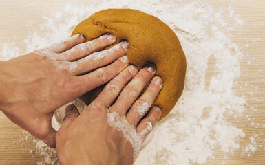Men's hands knead the dough. The chef prepares ginger. Christmas cookies on the table with cooking...