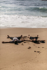 couple lying on wet sand near ocean on beach in portugal.