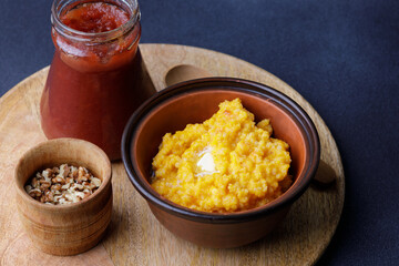 Sweet pumpkin porridge in clay bowl with jam and nuts