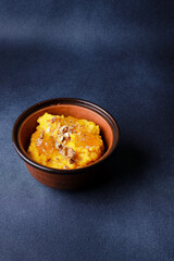 Sweet pumpkin porridge in clay bowl with jam and nuts