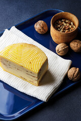 Fototapeta na wymiar A piece of cheese served with walnuts on the blue tray
