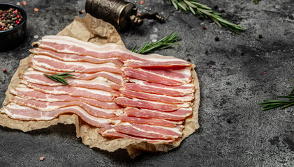 Close up Bacon slices. Pig meat. Pork belly with rosemary on a wooden board, Keto diet food...