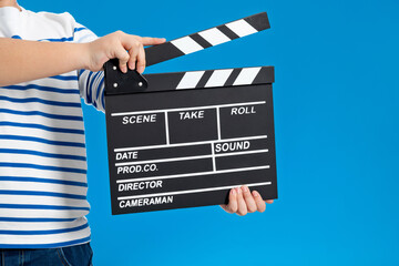 Woman hands holding cinema clapperboard on blue background