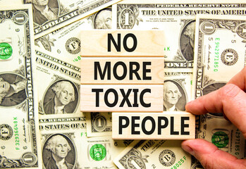 No more toxic people symbol. Concept words No more toxic people on wooden blocks on a beautiful background from dollar bills. Psychologist hand. Business, psychological no more toxic people concept.