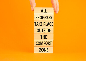 Progress symbol. Concept words All progress take place outside the comfort zone on wooden blocks on a beautiful orange background. Businessman hand. Business motivational and progress concept.