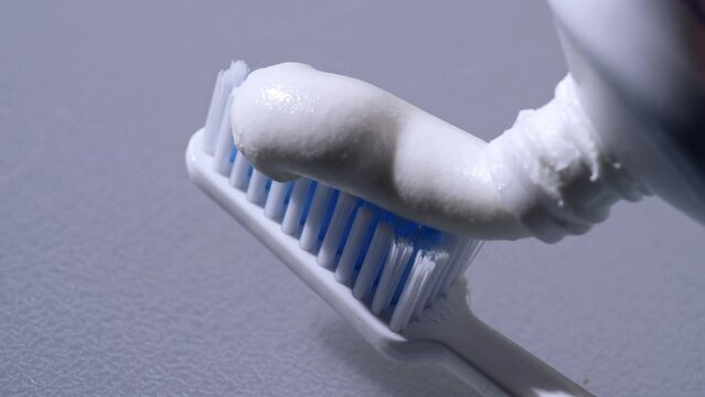 Squeezing toothpaste onto toothbrush