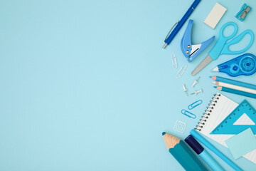 School and office supplies on blue background, template concept, top view