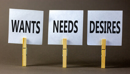 Wants needs and desires symbol. Concept words Wants Needs Desires on white papers on wooden clothespins. Beautiful grey background. Business wants needs desires concept. Copy space.