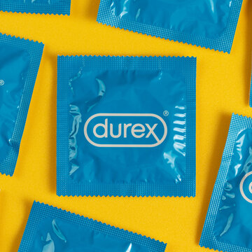 Lviv, Ukraine - August 02, 2022. Durex condoms on yellow background. Pattern, top view.
