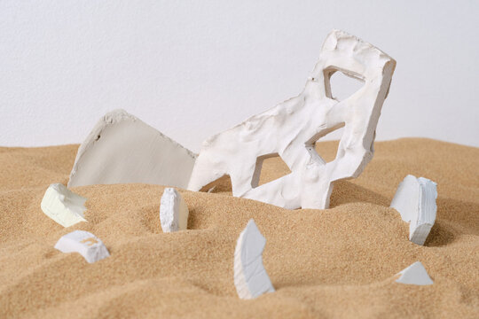 Horizontal studio shot of creative contemporary composition of white gypsum objects in sand, disaster concept