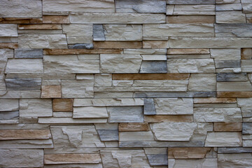 Gray decorative uneven cracked stone wall surface with cement.