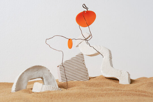 Horizontal close-up studio shot of creative installation of white gypsum objects, wire and plastic in sand, ruins concept