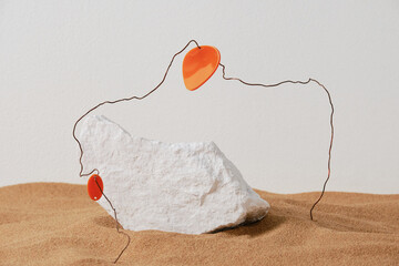 Horizontal close-up studio shot of creative composition of white stone, wire and plastic in sand, ruins concept